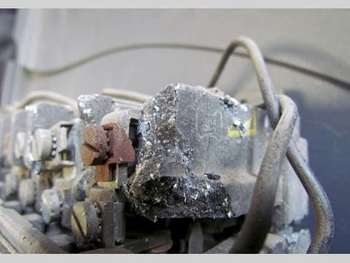 A close-up view of a motor control contactor, with asbestos fibers visible.